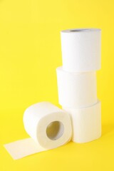 Many soft toilet paper rolls on yellow background