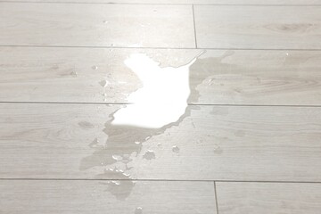 Puddle of spilled water on white laminated floor