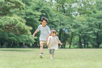 公園で追いかけっこする活発な子供達・兄妹・走る・短距離走
