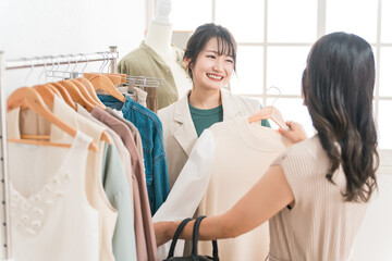 Obraz premium アパレルショップで洋服を買い物・ショッピングする女性とショップ店員 