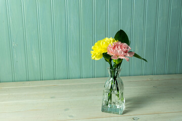 Yellow and peach carnation with greenery in a small delicate vase