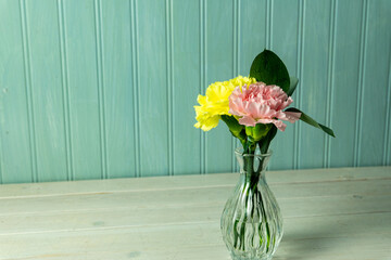 Yellow and peach carnation with greenery in a small delicate vase
