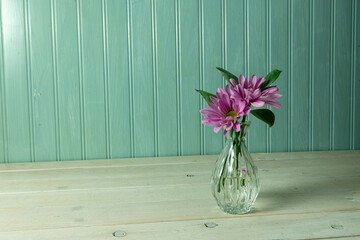 Purple daisies in a small delicate vase.