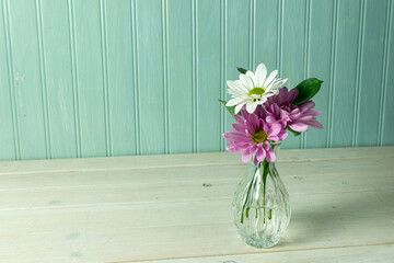 Purple and white daisies in a small delicate vase.