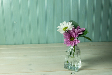 Purple and white daisies in a small delicate vase.