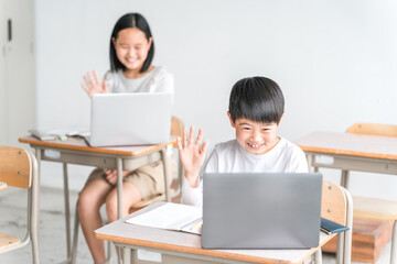 パソコンを使って勉強・学習する小学生の男の子と女の子（ICT教育・オンライン授業・オンライン学習）
