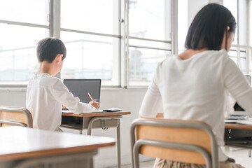 学校の教室で勉強をする小学生の男女（授業・教育・パソコン）
