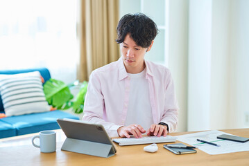 Fototapeta premium 部屋でパソコンの操作をする若い男性