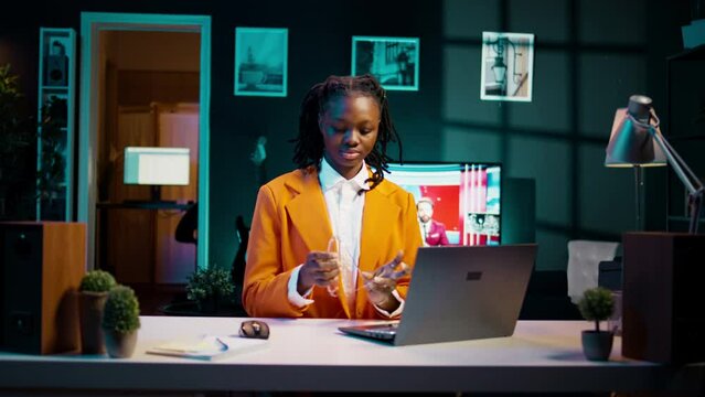Portrait of african american student putting glasses on and working on english essays at home, reading academic databases for additional resources. Young woman studying at university. Camera B.