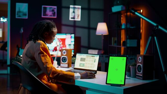 African american business student looking at isolated greenscreen, examining academic software spreadsheet to learn about tax services. Girl using tablet with blank copyspace layout. Camera B.