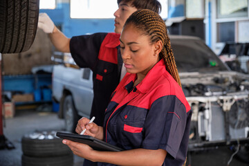 Young expert Black female inspects repair checklist with automotive mechanic worker partner,...