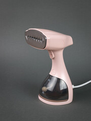 Light pink steamer for clothes on a gray background. - obrazy, fototapety, plakaty