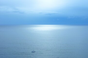Sunlight reflecting off the ocean on a clear day with a fishing ship in the foreground. 