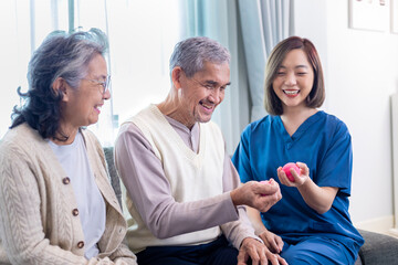 Senior couple get medical service visit from caregiver nurse while using round squishy ball for...