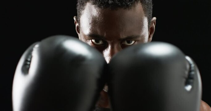Focused African American boxer ready to fight on black background