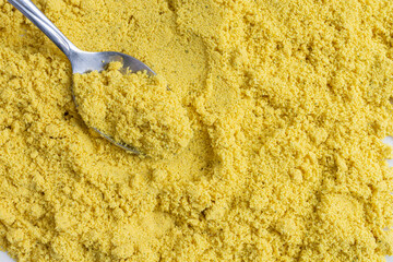 An abstract image of powdered chicken soup stock mixed with spices and metal spoon. 