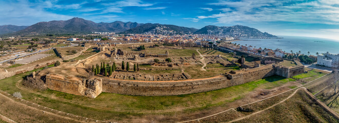 Panoramic aerial view of Roses citadel in Spain , giant pentagonal star fort fortress with bastions on each angle, ruins of medieval city, Roman ruins, monastery on the courtyard - obrazy, fototapety, plakaty