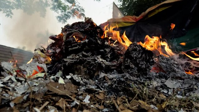 Burning garbage heap with flames and smoke environmental pollution concept roadside fire