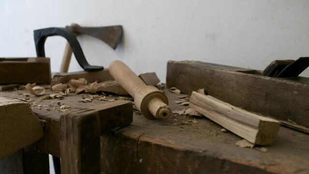 Closeup shot of the old carpenter tools on a wooden table by a white wall in a room in daylight