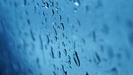 Raindrop on window blue background aqua bubble texture. Rainy water surface splash glass. Blurred background falling rain shower windy outdoors. Motion macro raindrops splash pattern design element