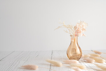 Vintage style of pastel natural colored, beige, and pink foxtail and dried flower in a vase against a white wooden backdrop with space for text. Spring and Autumn inspiration