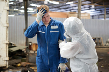 worker have a sick and coworker with personal protective equipment uniform(PPE) helping him in the...