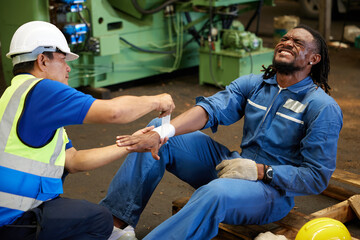 worker first aid and applying bandage on technician arm in the factory