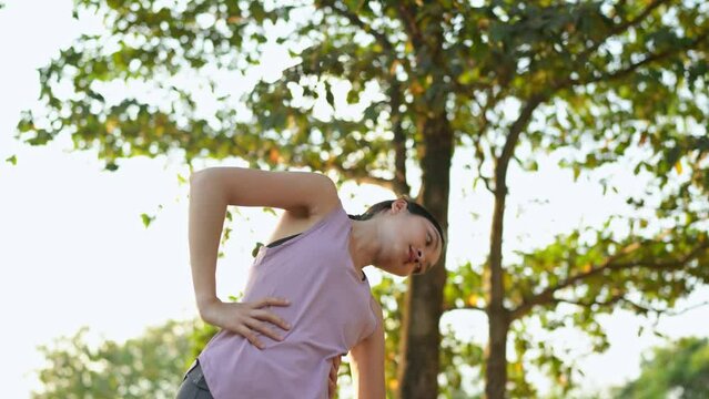 Health and healthy lifestyle of Asian woman in pink sportswear Preparing and stretching the muscles of the body and arms. Light sunlight. Running in the park. Exercise and live a balanced life.