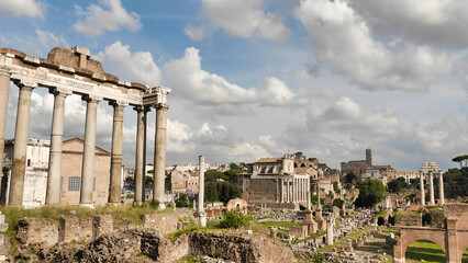 A view of the Roman Forum ruins, with the Basilica of Maxentius in the background, under a partly...