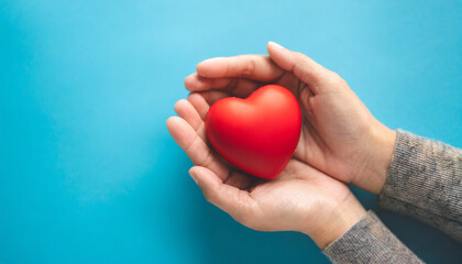 holding red heart symbol on blue backdrop, conveying love, care, and compassion