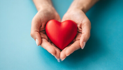 holding red heart symbol on blue backdrop, conveying love, care, and compassion