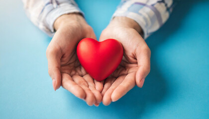 holding red heart symbol on blue backdrop, conveying love, care, and compassion