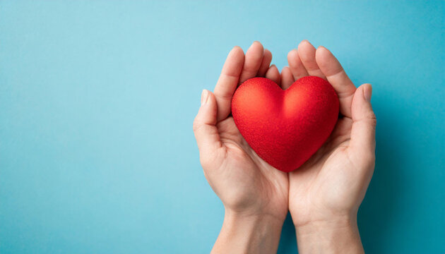 holding red heart symbol on blue backdrop, conveying love, care, and compassion