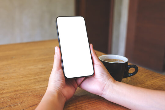 Mockup image of a woman holding mobile phone with blank desktop screen