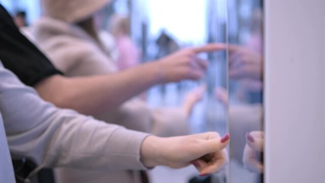 Girl swipes the screen making an order. Woman choosing dessert via self-service machine at fast food restaurant. Girl using touch terminal im restaurant makes a quick order through the self-service.