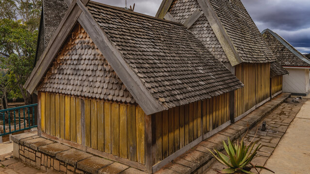 Ancient royal tombs with the remains of the rulers of Imerina. The houses with triangular roofs are built of unpainted wood. Madagascar. Antananarivo. Royal Hill of Ambohimanga