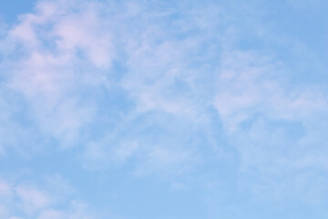 Blue sky background with pale pink clouds at sunset