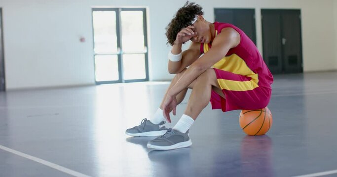 Young African American man sits dejected on a basketball court