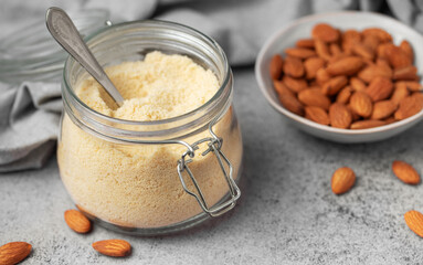 Fresh almond flour in a  glass jar and almonds