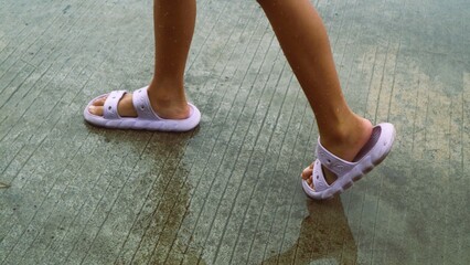 children's feet wearing slippers stepping on puddles of water