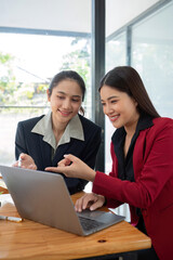 Two businesswomen discussing project strategy in office conference room Businesswoman discusses project planning with colleagues in modern workplace, gives advice on financial data report