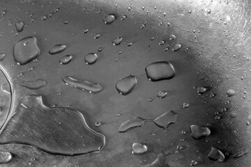 WATER DROPLETS ON A CURVED METAL SURFACE . BLACK AND WHITE PHOTO