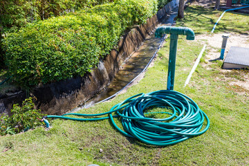 Green garden hose on the ground, summer outdoor day light