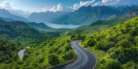 A serene winding road cutting through a vibrant green landscape, with misty mountains in the distance.
