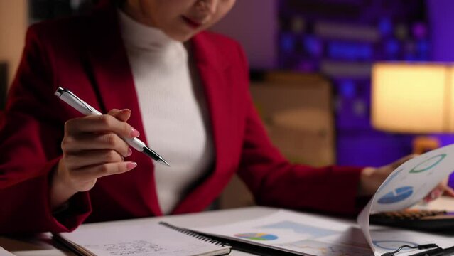 Businesswoman sitting and taking notes in a notebook, recording on a laptop to check company finances income and budget Calculate monthly expenses, manage budget, loan, invoice. Finance concept.