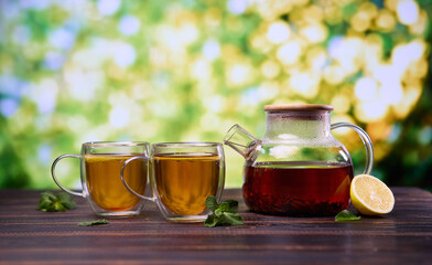 natural organic herbal tea in glass teapot and cup on a wooden table
