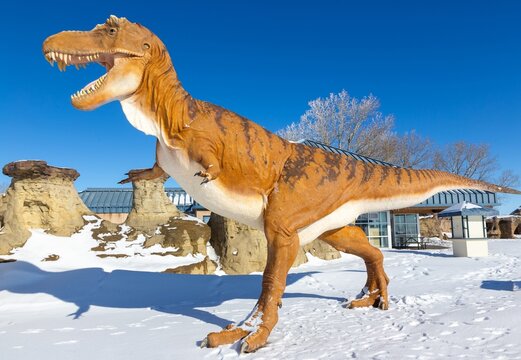 Milk River, Alberta, Canada - February 14, 2024: Massive Dinosaur Model Walking by Hoodoo Rock Formations in Tourist Welcome Visitor Center