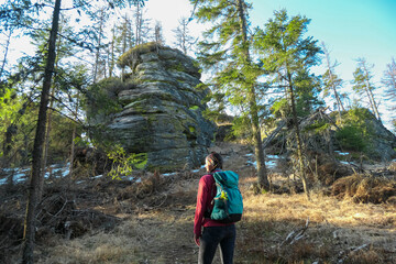 Hiker woman with scenic view of massive rock formation Grossofen in idyllic forest in Modriach, Hebalm, Kor Alps, border Carinthia Styria, Austria. Refreshing hiking trail in remote Austrian Prealps