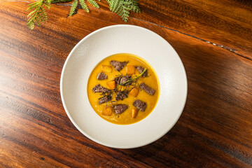 Thick sirloin soup in a hotel restaurant. Meal on wooden table. Delicious soup with spices.