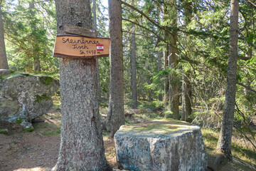 Information sign in front of rock with flat surface resembling table. Board in German language...